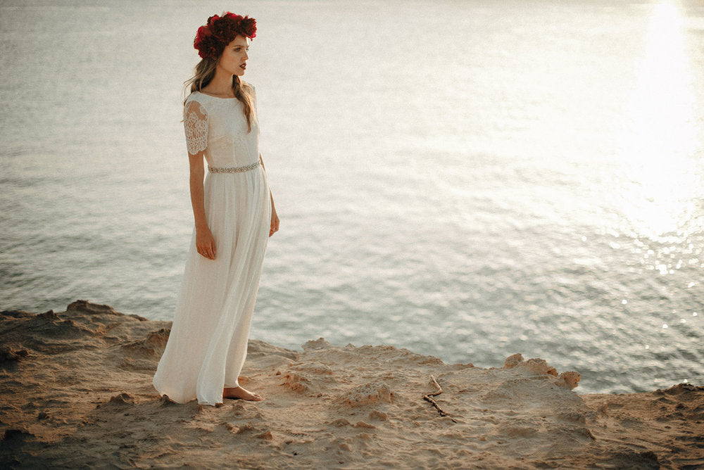 Woman stood by the sea in the beach dress, designed by luna bride.